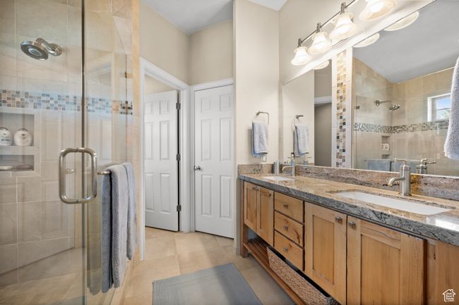 Full bathroom featuring double vanity, tile patterned floors, a stall shower, and a sink | Image 21