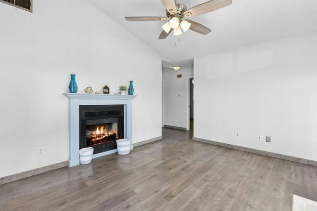 living room featuring light wood-type flooring, a lit fireplace, high vaulted ceiling, and ceiling fan | Image 7