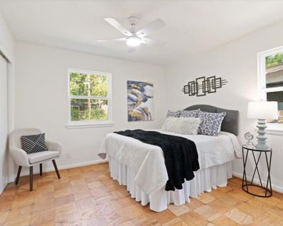 Bedroom featuring multiple windows, ceiling fan, and light parquet floors | Image 2