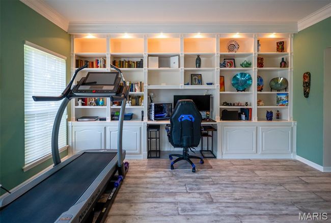 Home office with crown molding, wood finished floors, and built in study area | Image 5