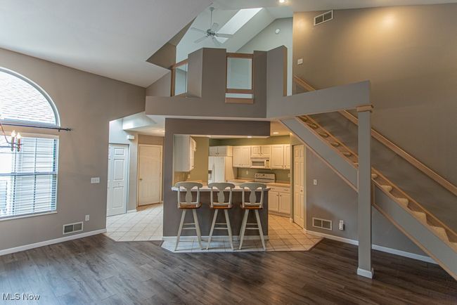 Dining area with a skylight, light wood-style flooring, stairs, ceiling fan, and high vaulted ceiling | Image 16