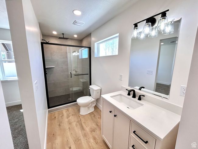 Full bathroom featuring a stall shower, toilet, recessed lighting, wood finished floors, and vanity | Image 9