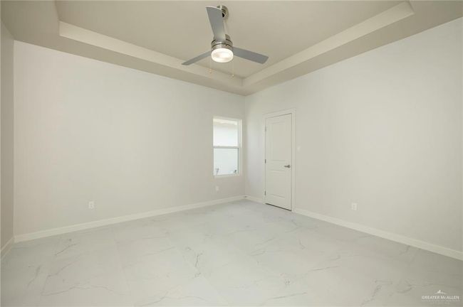 Empty room featuring a raised ceiling, light marble finish flooring, baseboards, and ceiling fan | Image 16