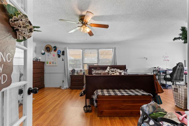 Bedroom with a textured ceiling, light wood finished floors, and a ceiling fan | Image 21