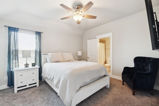 Carpeted bedroom featuring vaulted ceiling, ensuite bath, and a ceiling fan | Image 24
