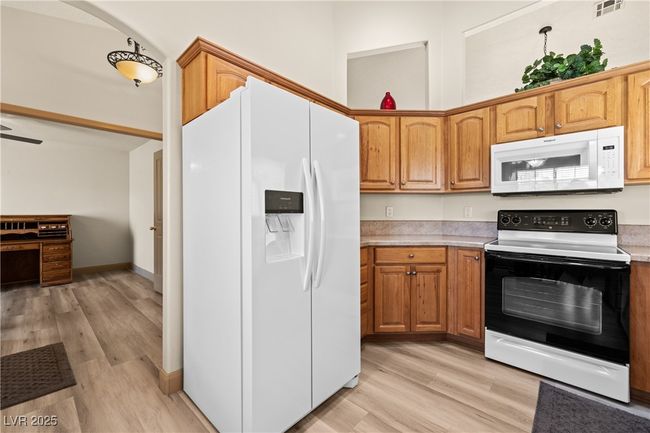 Kitchen with white appliances, light countertops, light wood-style flooring, and brown cabinetry | Image 14