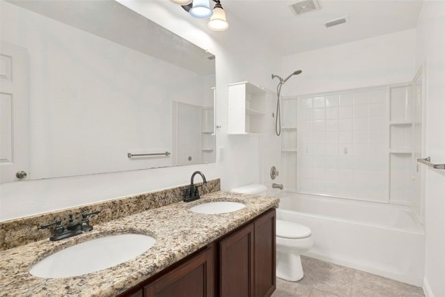 Bathroom featuring toilet, double vanity, shower / washtub combination, and tile patterned flooring | Image 30