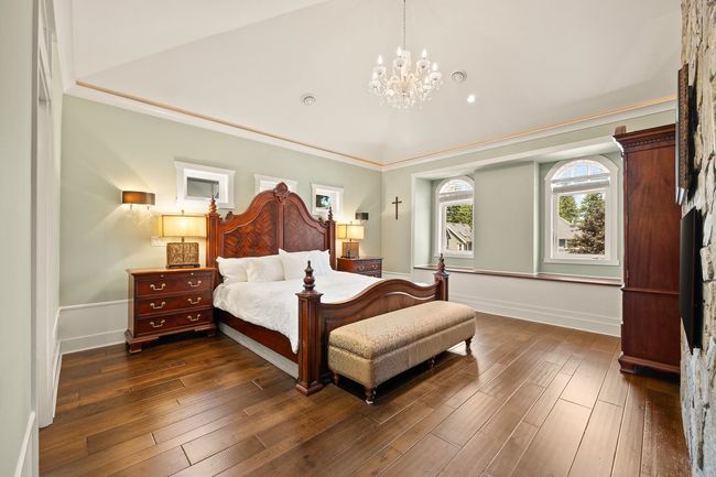 Bedroom with a chandelier, dark wood-style flooring, crown molding, and lofted ceiling | Image 13