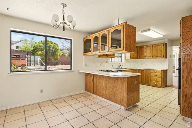 Kitchen with a peninsula, healthy amount of natural light, light countertops, a chandelier, and a textured ceiling | Image 12