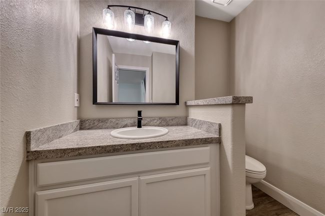Half bathroom featuring vanity, a textured wall, and wood finished floors | Image 29
