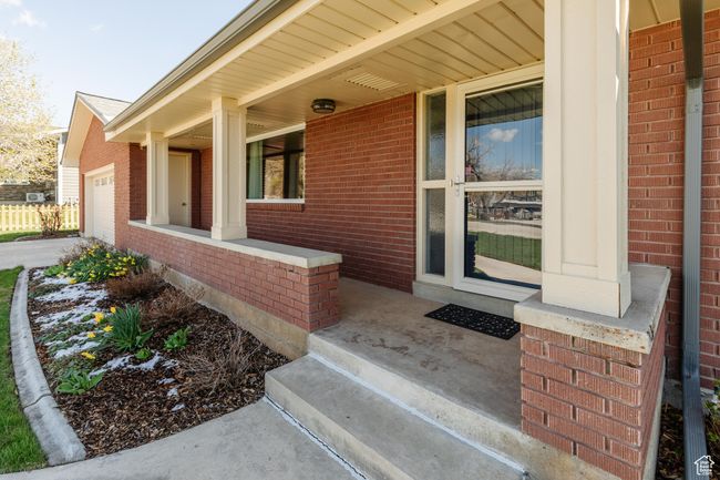 Entrance to property with an attached garage, brick siding, and covered porch | Image 35