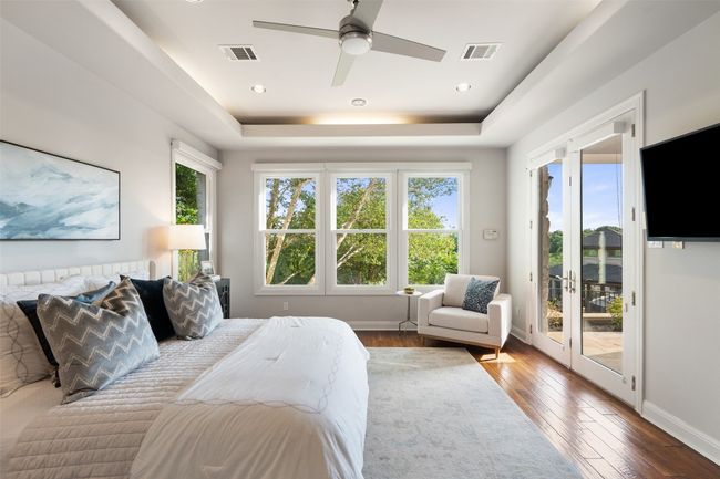 Bedroom featuring access to exterior, hardwood / wood-style floors, a tray ceiling, baseboards, and ceiling fan | Image 19