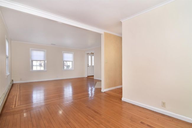 Dining area view to Living room featuring baseboards, baseboard heating, ornamental molding, and light wood finished floors | Image 5