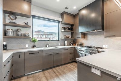 Kitchen featuring backsplash, sink, light wood-type flooring, and range with two ovens | Image 2