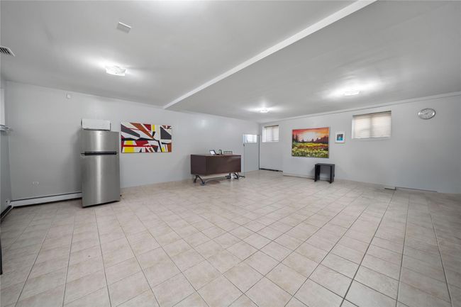 Below grade area with light tile patterned floors, visible vents, baseboard heating, and freestanding refrigerator | Image 22