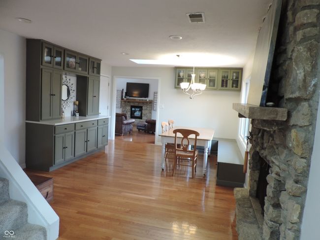 dining area featuring stairway, a fireplace, a notable chandelier, and light wood-type flooring | Image 13