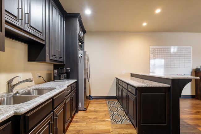 Kitchen featuring light wood finished floors, a peninsula, recessed lighting, and stainless steel refrigerator with ice dispenser | Image 14