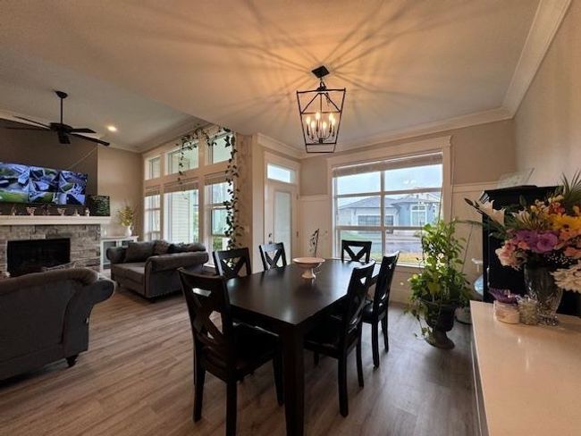 Dining room with wood finished floors, ceiling fan with notable chandelier, a fireplace, ornamental molding, and recessed lighting | Image 22