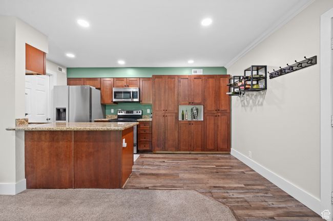 Kitchen featuring appliances with stainless steel finishes, ornamental molding, recessed lighting, brown cabinets, and a peninsula | Image 5