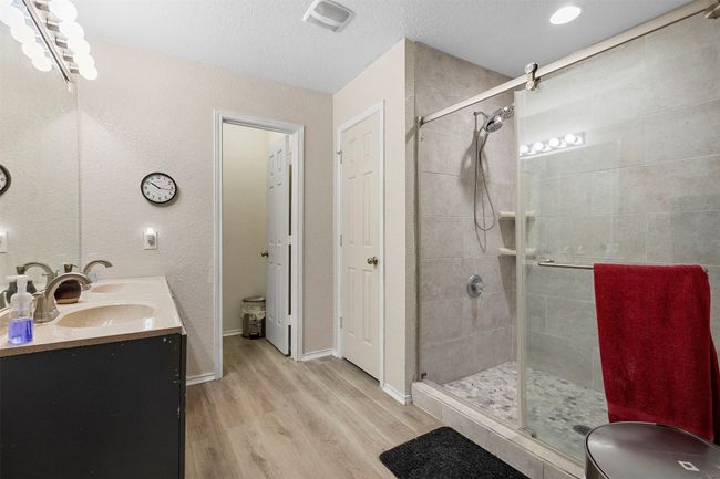 Full bath featuring a stall shower, wood finished floors, a textured ceiling, visible vents, and double vanity | Image 25
