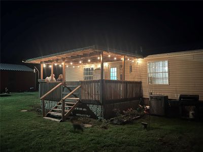 Back house at night featuring a deck, central AC, a pergola, and a lawn | Image 2