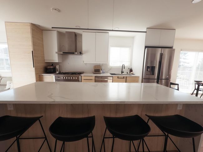 Kitchen featuring stainless steel appliances, wall chimney range hood, a sink, and plenty of natural light | Image 5