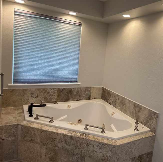 Luxurious corner soaking tub with new tile surround and modern plumbing fixtures. | Image 8