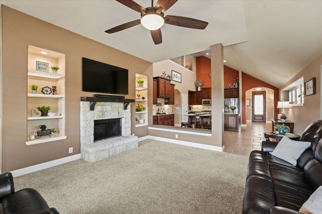 Living room with built in shelves, ceiling fan, arched walkways, and baseboards | Image 16