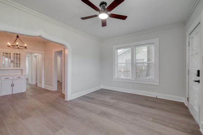 Spare room featuring a chandelier, a ceiling fan, ornamental molding, light wood-style flooring, and arched walkways | Image 25