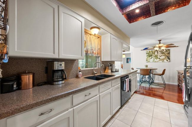 Kitchen with a ceiling fan, black dishwasher, light tile patterned flooring, a sink, and backsplash | Image 13