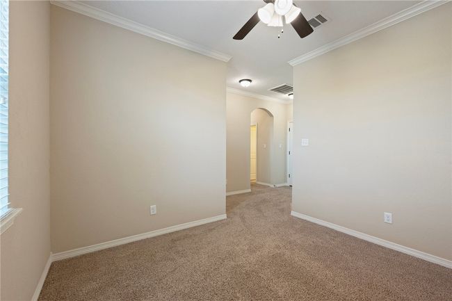 Empty room with ceiling fan, arched walkways, light colored carpet, and ornamental molding | Image 19