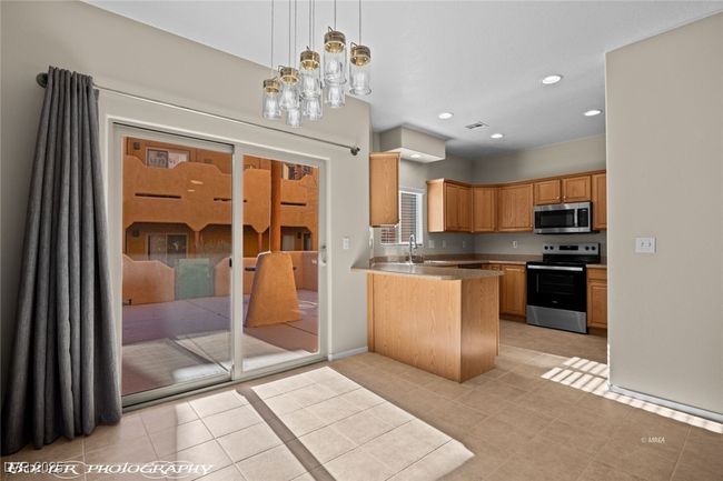 Kitchen featuring a peninsula, stainless steel appliances, recessed lighting, a sink, and hanging light fixtures | Image 8
