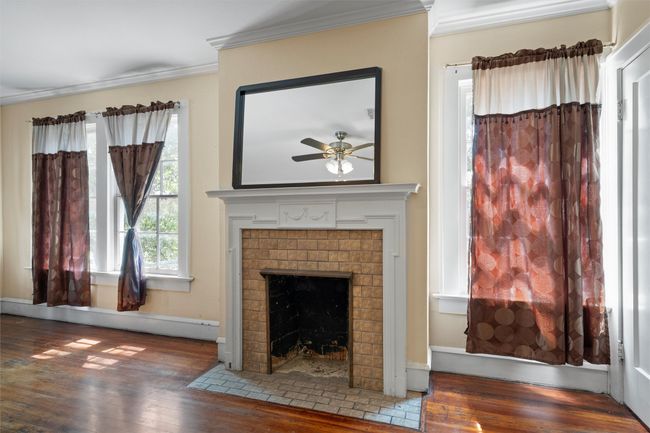 Unfurnished living room with hardwood / wood-style floors, ornamental molding, a brick fireplace, and a baseboard heating unit | Image 22