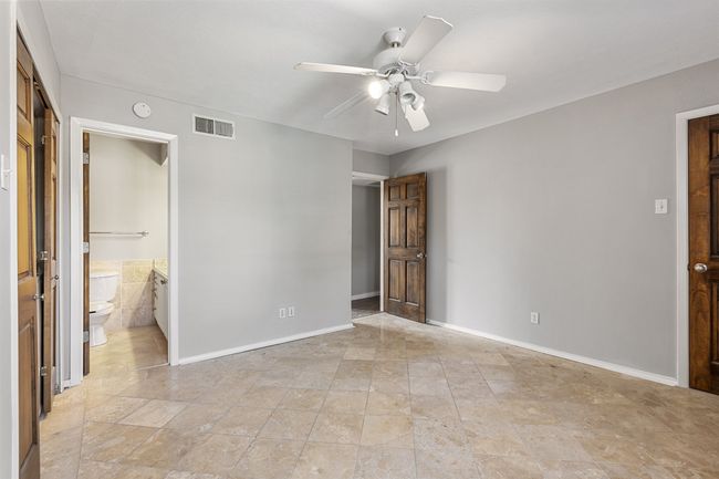 Unfurnished bedroom with visible vents, baseboards, ensuite bathroom, ceiling fan, and stone finish floor | Image 18