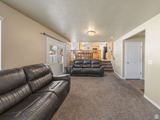 Living room featuring dark colored carpet, stairs, and a textured ceiling | Image 11