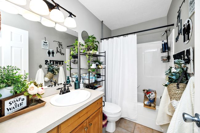 Main guest bathroom featuring shower / tub combo, tile patterned floors, vanity, and toilet | Image 21