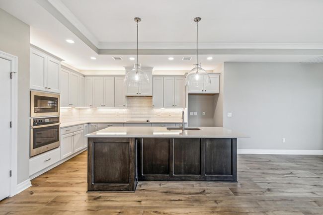Kitchen featuring sink, white cabinetry, an island with sink, and light hardwood / wood-style flooring | Image 5