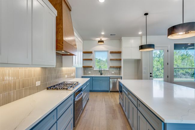 Kitchen featuring open shelves, a sink, white cabinetry, stainless steel appliances, and custom range hood | Image 10