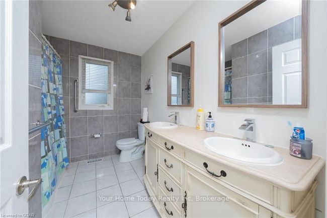 Bathroom featuring curtained shower, tile patterned floors, toilet, vanity, and tile walls | Image 31
