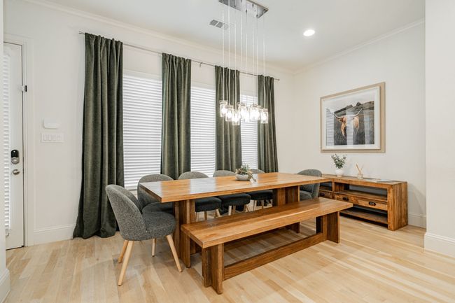 Dining space with crown molding, light wood finished floors, stylish dining furniture & decor, and a chandelier | Image 14