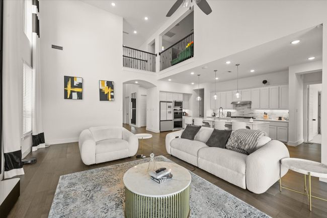 Living area with a ceiling fan, arched walkways, dark wood-style flooring, a towering ceiling, and recessed lighting | Image 7