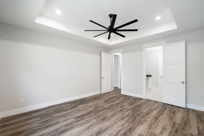Unfurnished bedroom featuring a tray ceiling, connected bathroom, ceiling fan, and wood-type flooring | Image 20