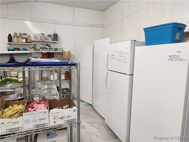 Closed room with sink currently being used as storage area for supplies and freezer space. | Image 20