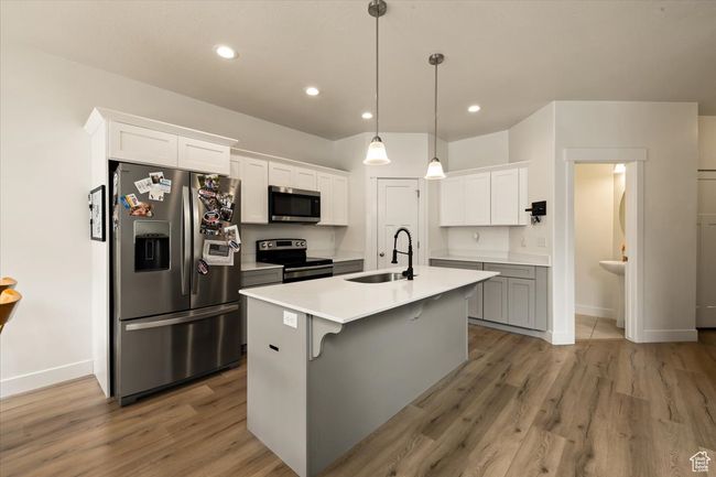 Kitchen featuring light wood finished floors, stainless steel appliances, baseboards, and a sink | Image 9