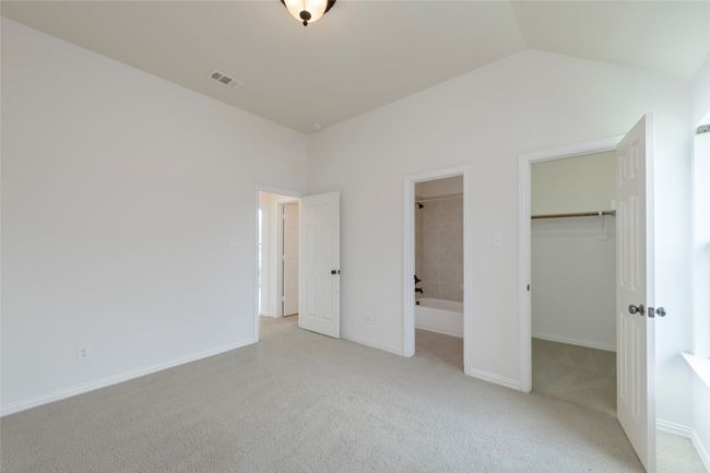 Unfurnished bedroom with a walk in closet, carpet flooring, a closet, and lofted ceiling | Image 32