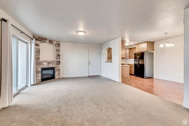 Unfurnished living room featuring light carpet, a fireplace, and a chandelier | Image 6