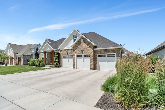 View of front facade featuring driveway, stone siding, a garage, and a front yard | Image 4