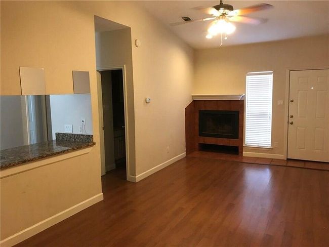 Unfurnished living room featuring baseboards, visible vents, a tiled fireplace, and wood finished floors | Image 5