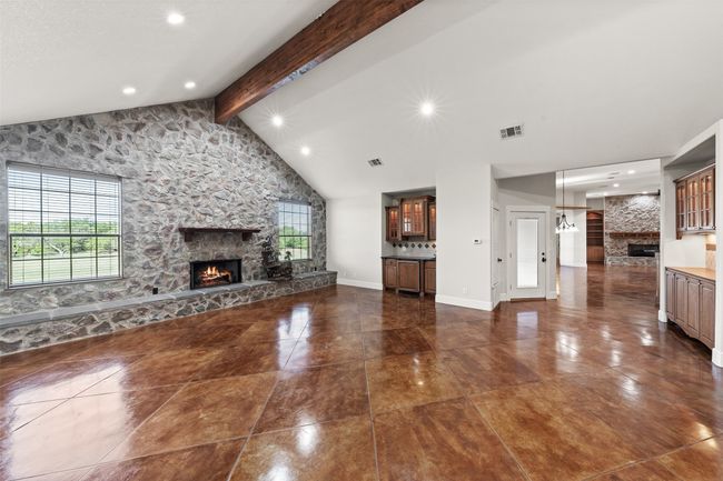 Unfurnished living room with a fireplace, beam ceiling, recessed lighting, baseboards, and high vaulted ceiling | Image 12
