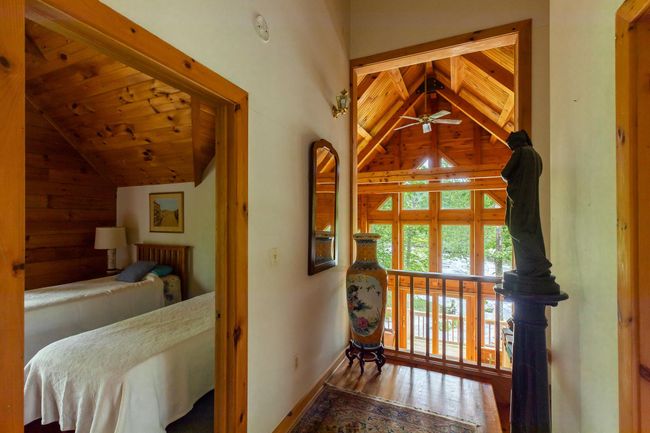 Bedroom with wood finished floors, baseboards, wooden walls, wood ceiling, and high vaulted ceiling | Image 15